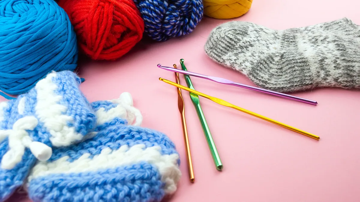 Wooden knitting needles with a ball of soft angora wool resting beside them.