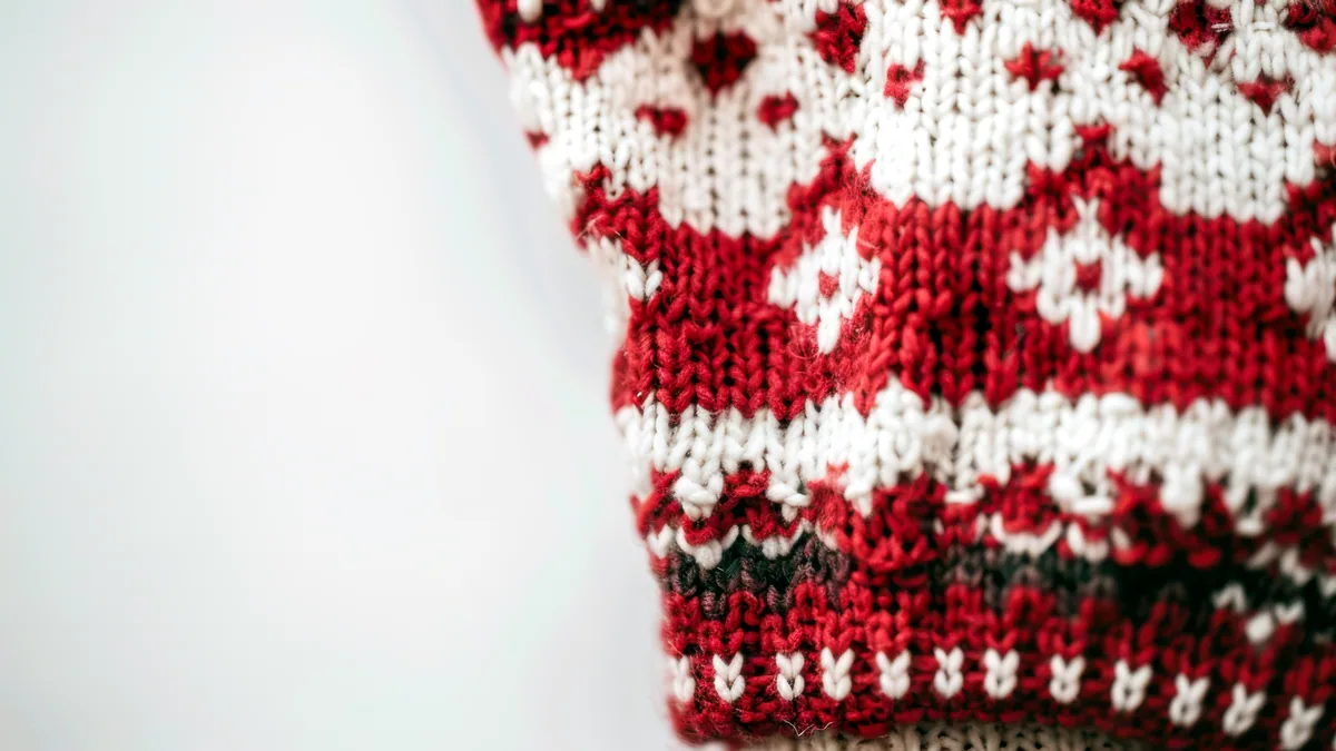 A classic red and white knit winter top folded on a retail shelf.