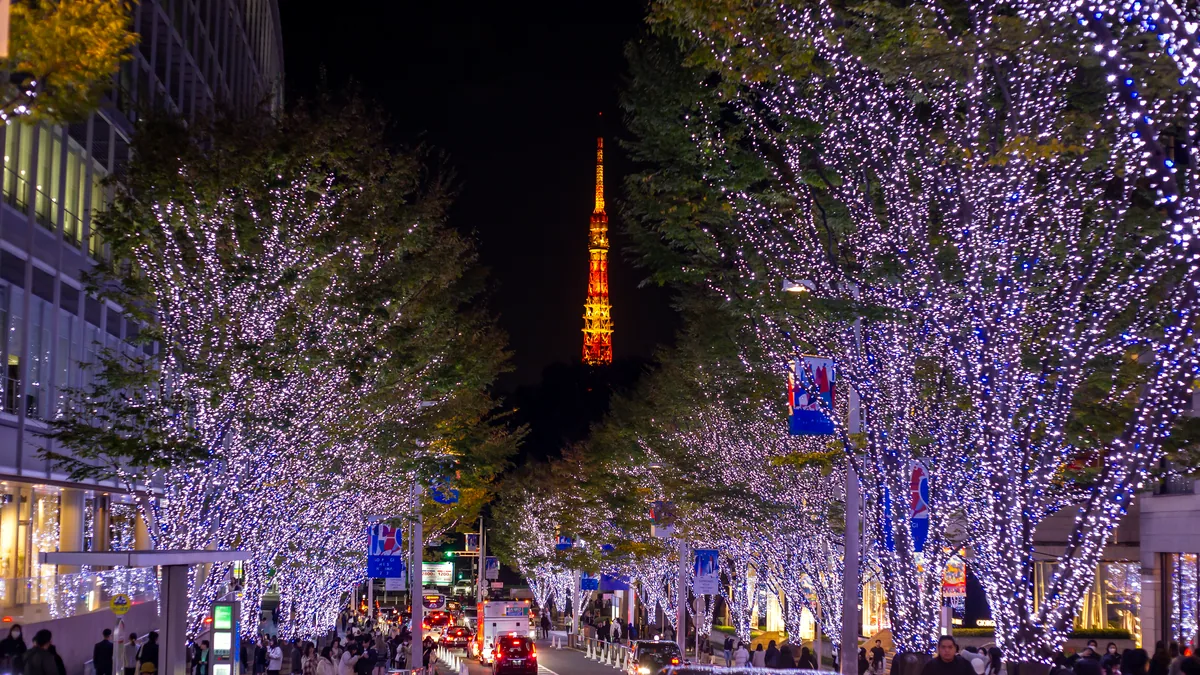 A busy Tokyo street in winter at dusk, shop lights glowing in the cold air.