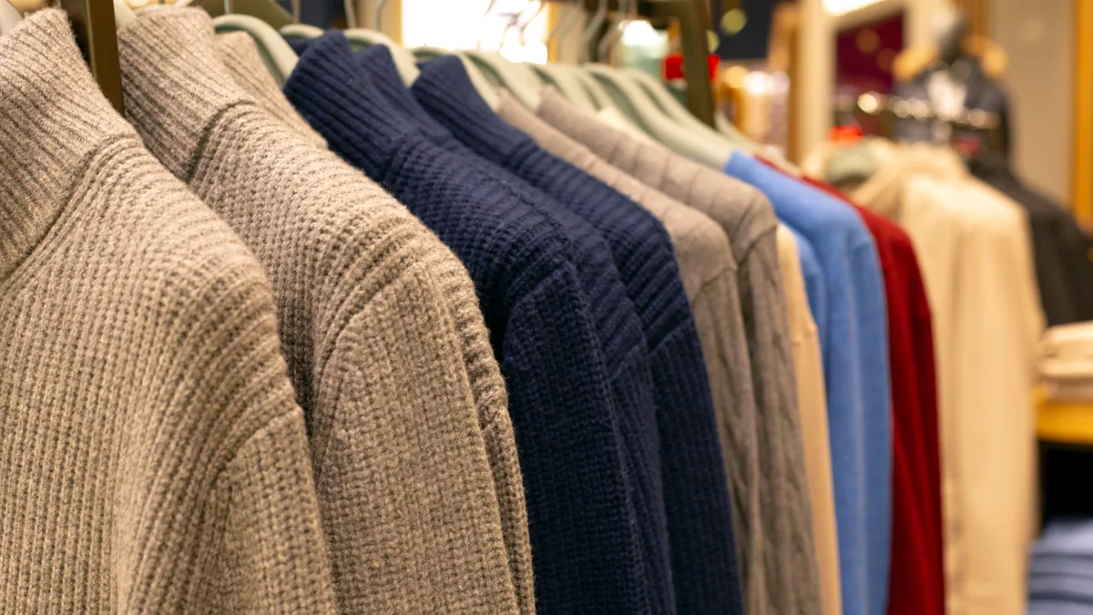 A department store knitwear display with neatly arranged jumpers in muted tones.