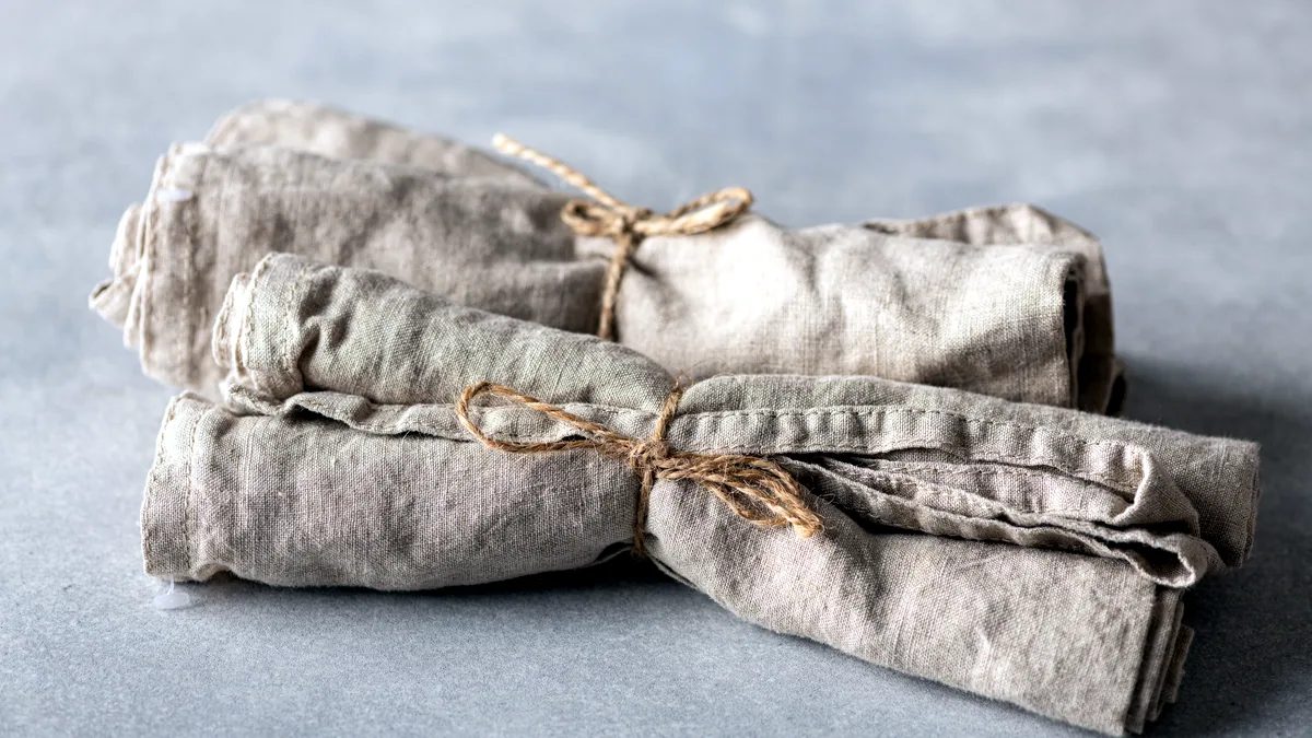 A folded piece of natural linen fabric with a dry, open weave in beige.